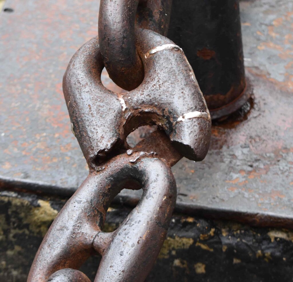 An almost broken chain link connected to a pole.