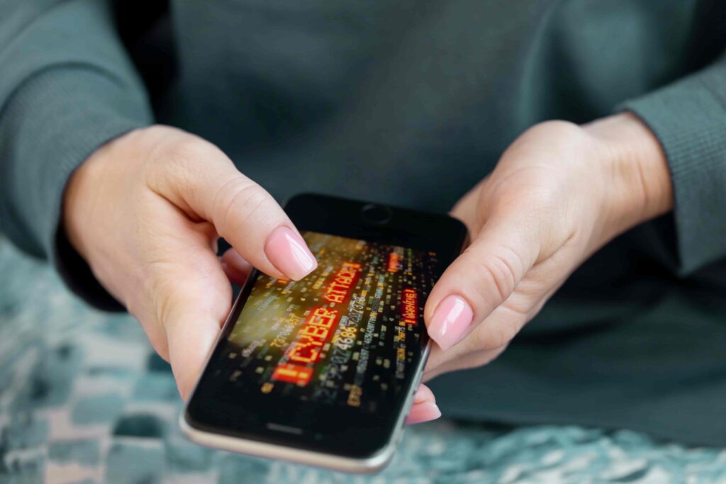 A person holding a phone showing the word Cyber Attack